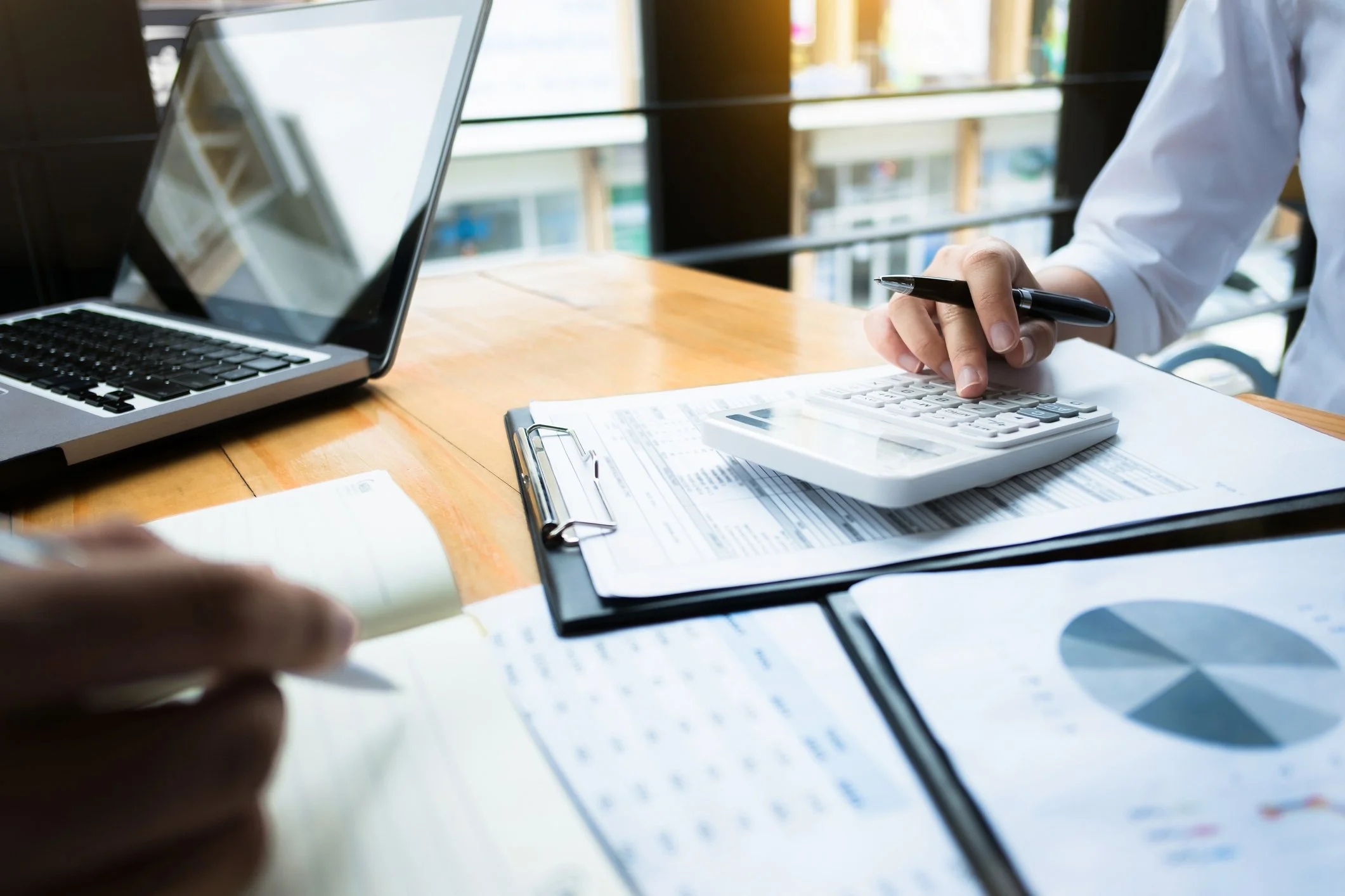A business owner reviewing tax projections with a calculator and laptop